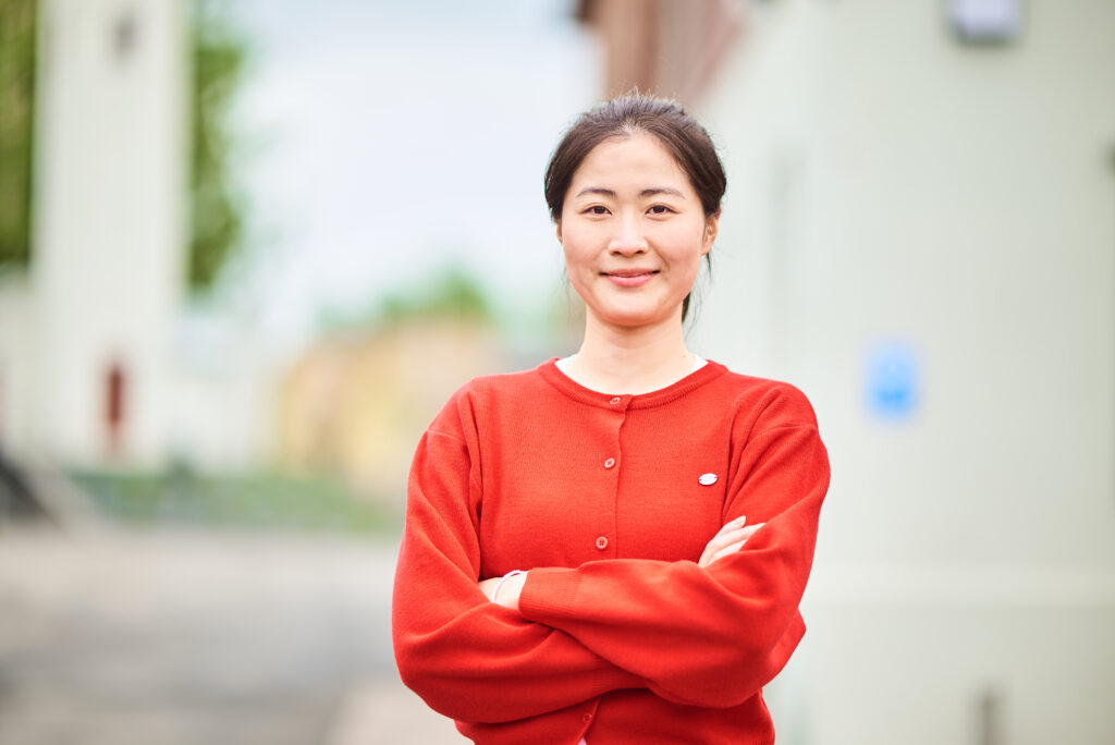 Punaiseen puseroon pukeutunut nainen seisoo ulkona.